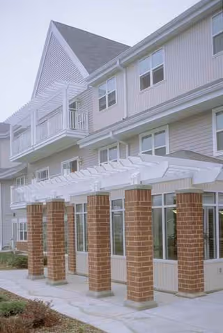 Exterior view of a multi-story senior apartments building with brick columns and glass entryway.