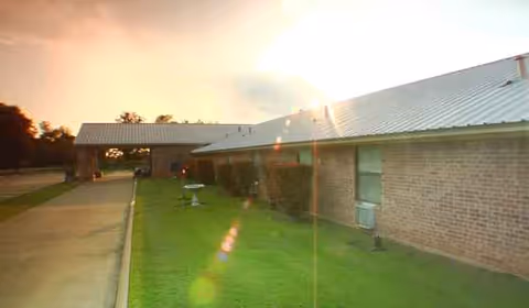 Exterior view of a single-story brick nursing home with a green lawn and walkway.