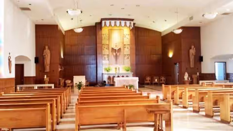 Wooden pews facing an altar in a church-like chapel with statues.