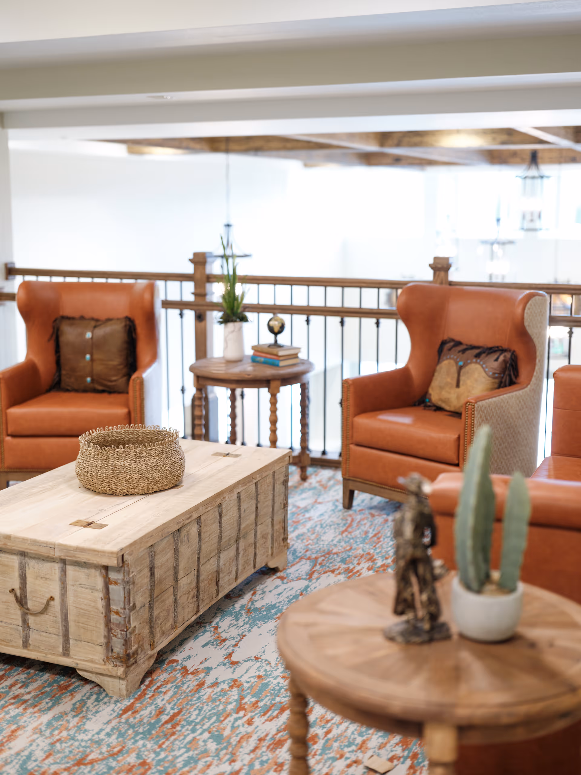 Cozy seating area with leather wingback chairs, wooden coffee tables, and decorative accents on a patterned rug.