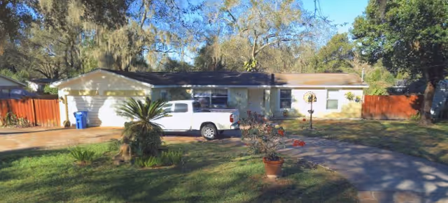 A single-story house with a white pickup truck in the driveway and front yard.