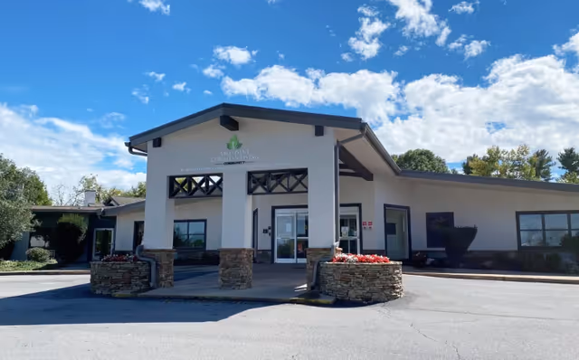A one-story senior living facility front entrance with stone columns and clear signage.