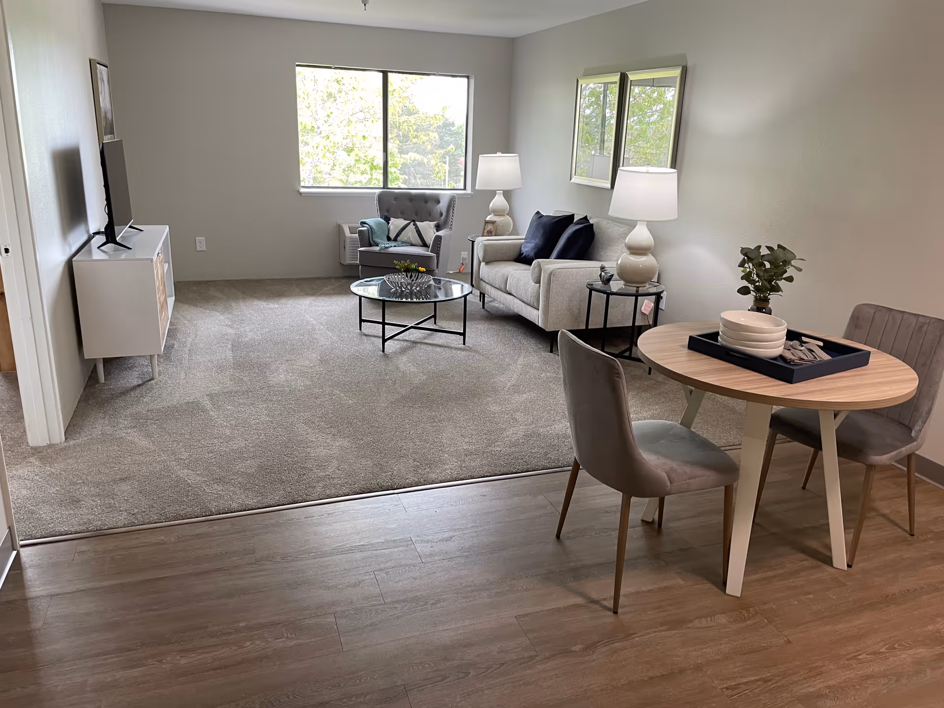 Bright, modern living room in a senior facility with sofa, chairs, and dining table.