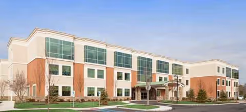 Exterior view of a modern senior living facility with brick walls and glass windows.
