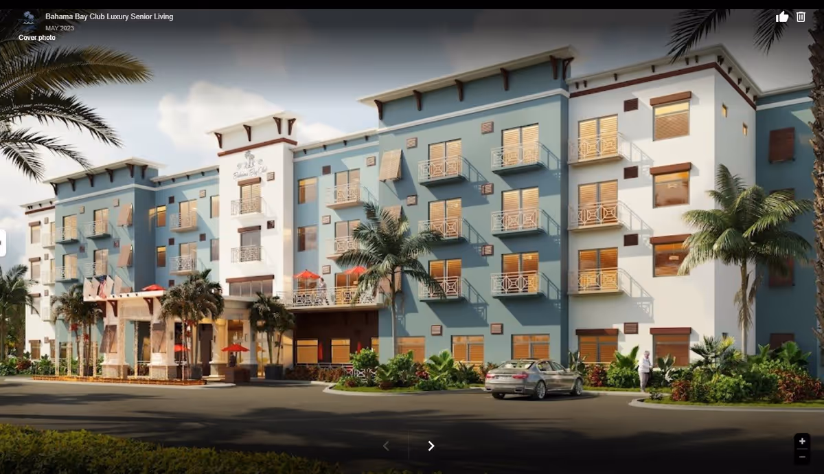 Exterior front view of a four-story Bahama Bay Club senior living building with balconies, palm trees, and a parked car.