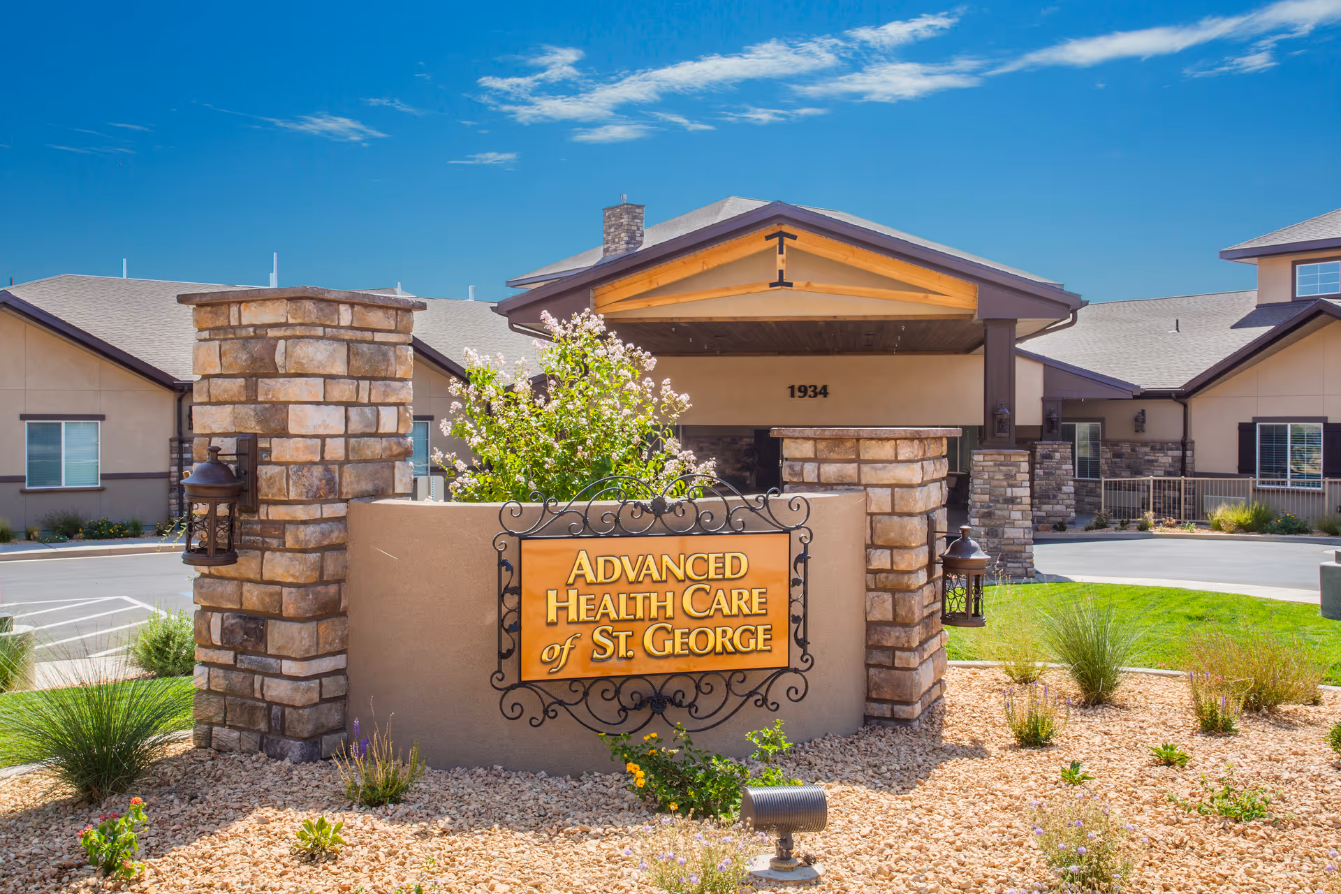Entrance of Advanced Health Care of St. George showing a stone sign and pillars with the facility building behind under a blue sky.