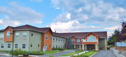 Exterior view of a multi-section senior living facility with a curved driveway and entrance.