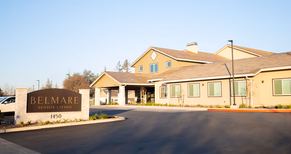Exterior view of Belmar Senior Living with driveway and large sign in front.
