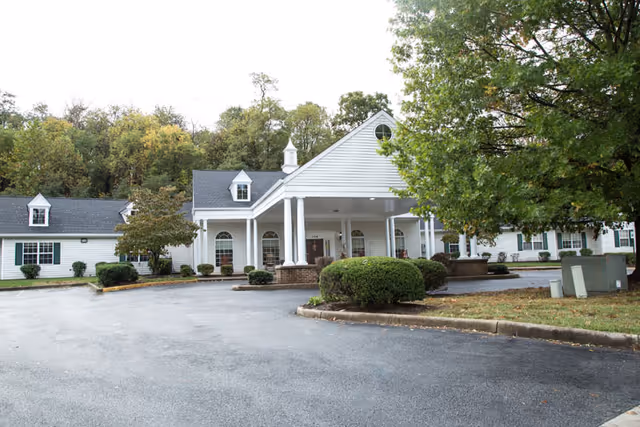 White Lavender Hills Front Royal Campus building with a covered entrance and trees.