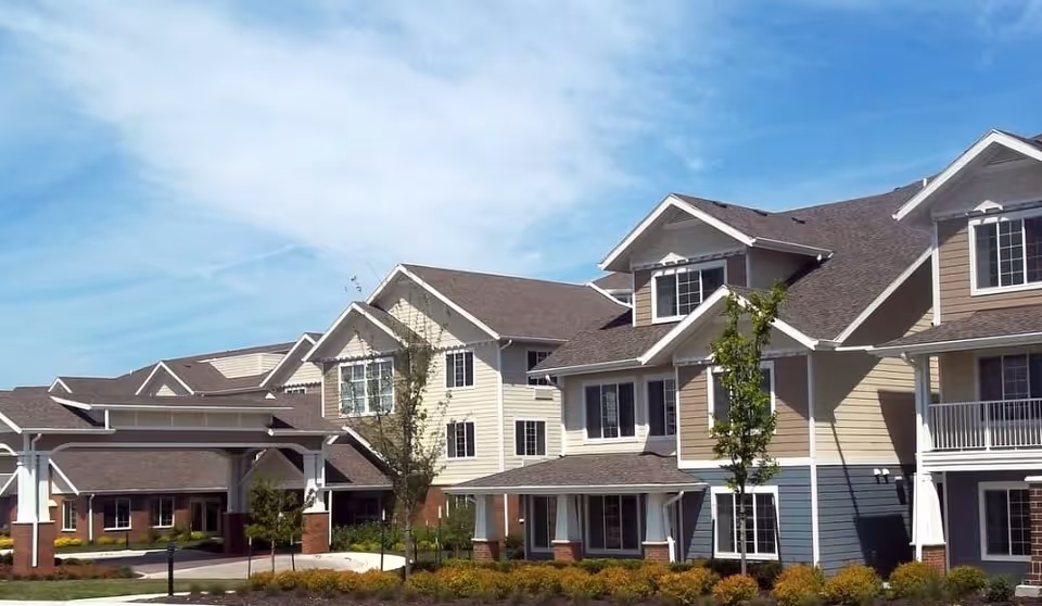Exterior view of a multi-story Meadowlark Estates senior living complex with gabled roofs, balconies, and landscaped grounds.