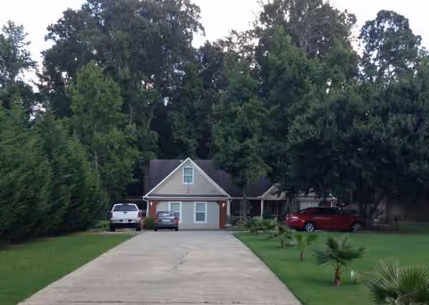 Front view of a single-story building with driveway and parked cars.