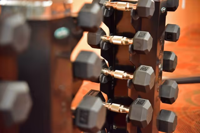 Close-up of a vertical rack holding multiple hexagonal dumbbells in a fitness area.