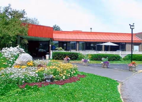 Exterior view of Maine Veteran's Home with a red roof, garden, and walkway.