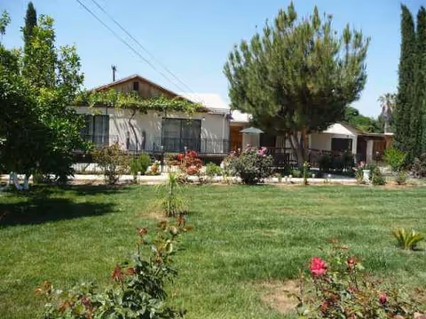 Single-story building with a manicured lawn, trees, and garden in front.