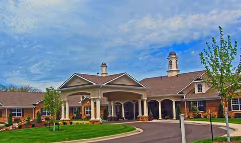 Exterior view of a brick senior living facility with arched entry and curved driveway.