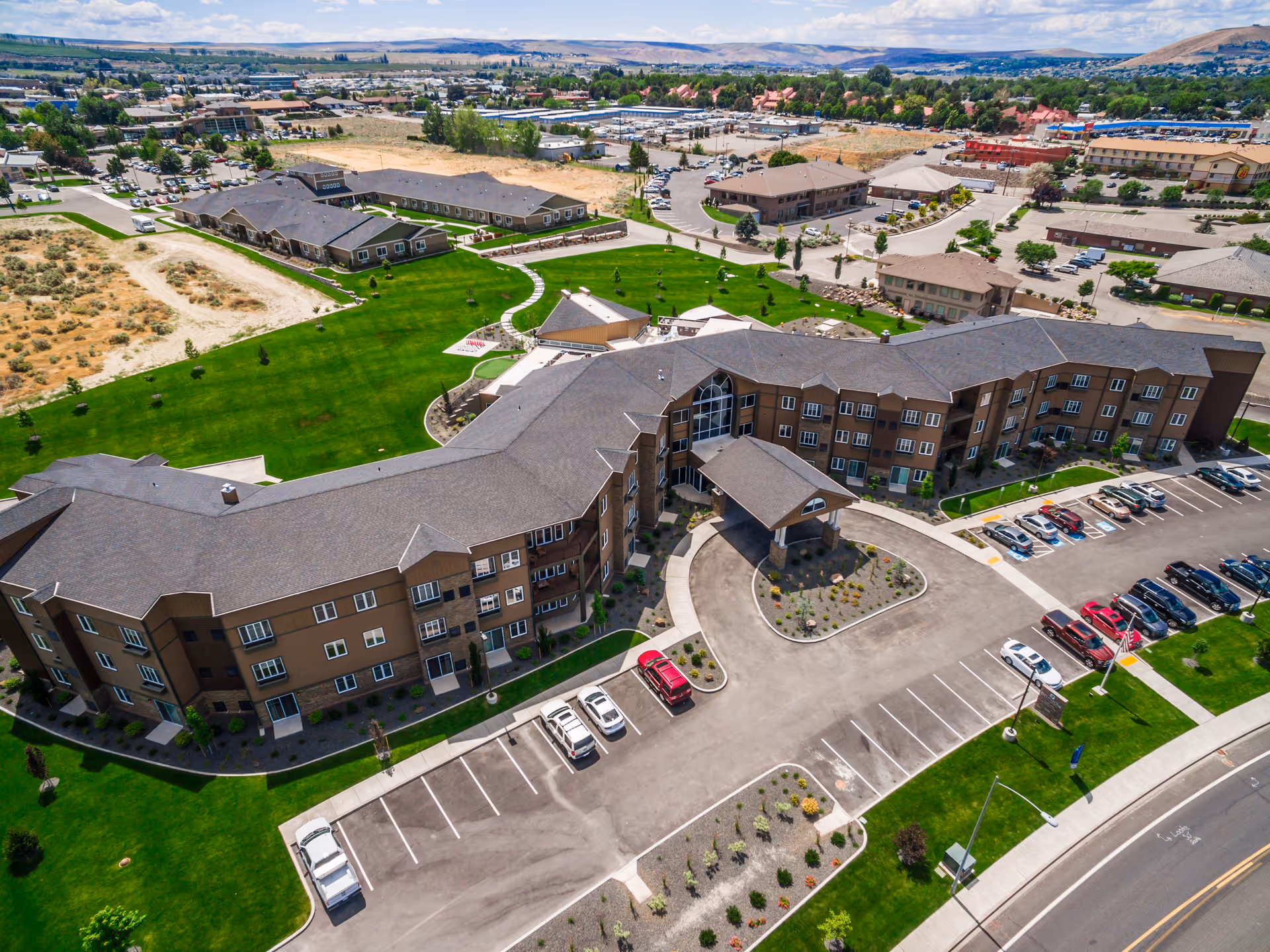 Aerial view of the Ciel of Tri-Cities Memory Care building complex with landscaped lawns, parking lot, and main entrance canopy.