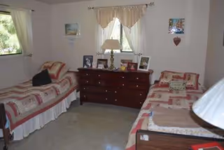 Two twin beds with patchwork quilts flank a wooden dresser under windows.