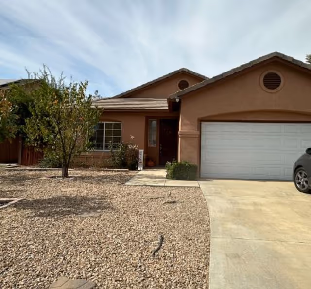 Front exterior view of a single-story tan home with a two-car garage.