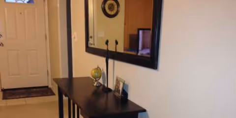 Entry hallway featuring a dark console table, globe, and wall mirror.