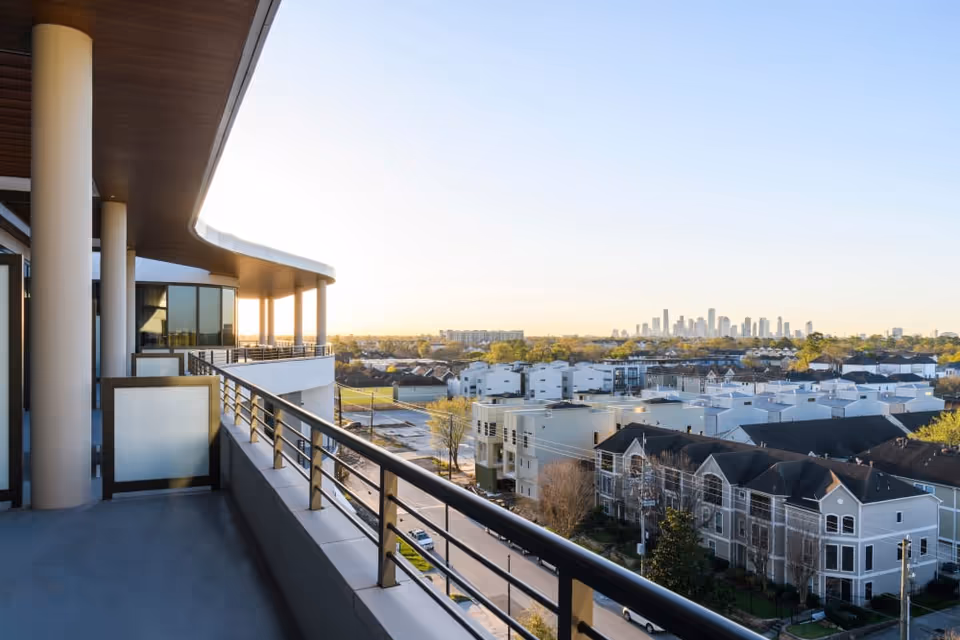 View from a balcony of Clearwater at The Heights showing a city skyline in the distance, residential buildings, and a clear sky during sunset.
