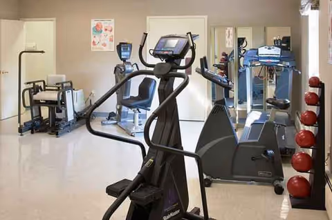 Interior senior living gym with treadmills, a stationary bike, and various exercise equipment.