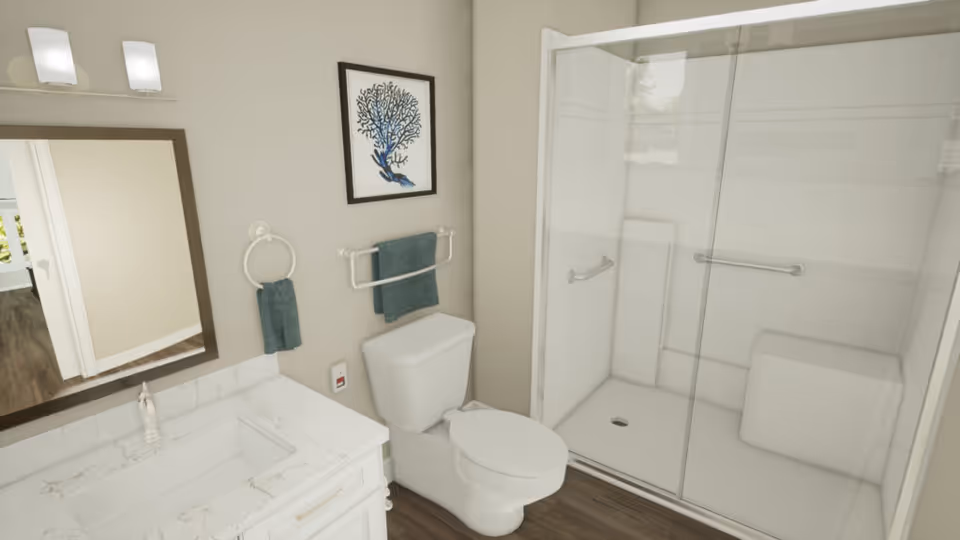 Bright accessible bathroom with a vanity and mirror, toilet, and a glass-enclosed walk-in shower with grab bars.