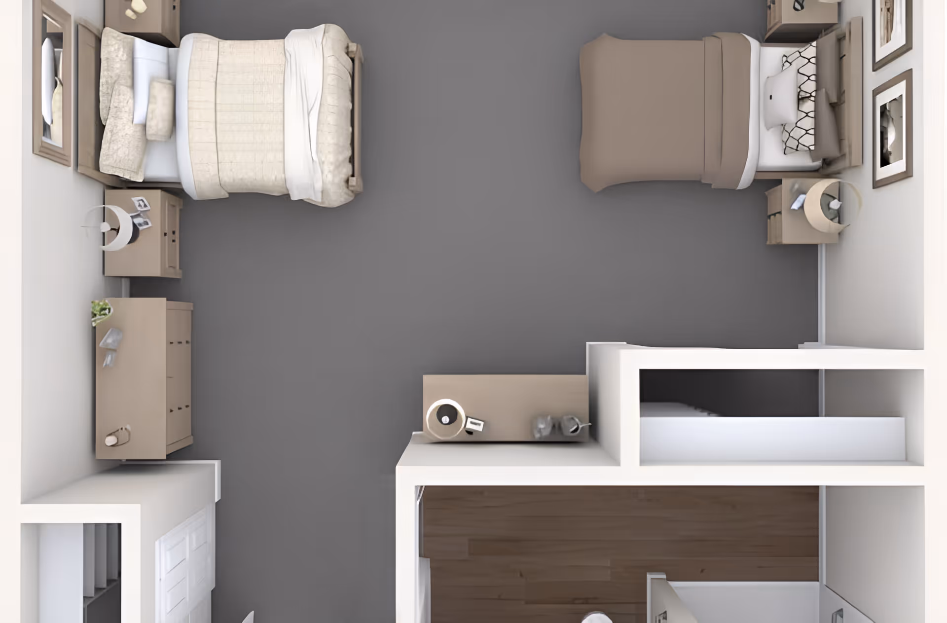 Top-down view of a bedroom layout with two beds, each with a nightstand and lamp. The room has a dresser, a small table, and framed pictures on the walls. The floor is carpeted in gray, and there is a small section of hardwood flooring visible near the entrance.