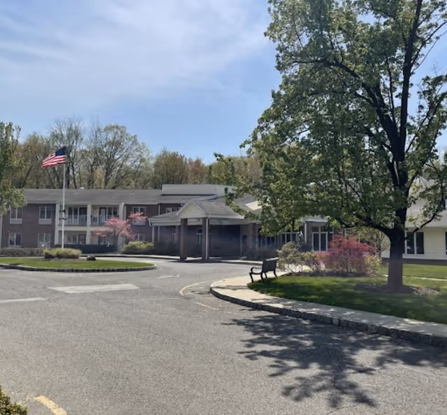 Front exterior view of Mira Vie at Montville, showing the driveway, flag, and trees.