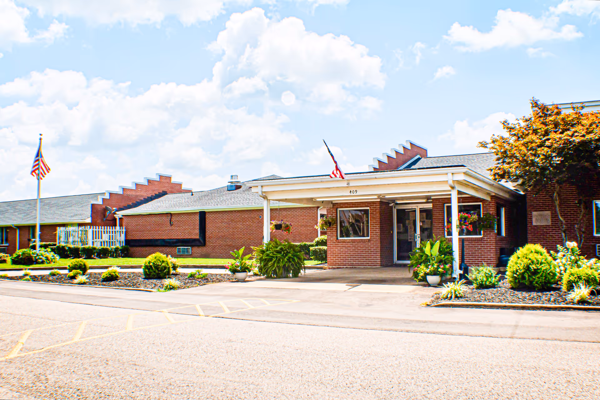 Exterior view of the Adamsville Healthcare and Rehabilitation Center, featuring a brick facade, landscaping, and American flags.