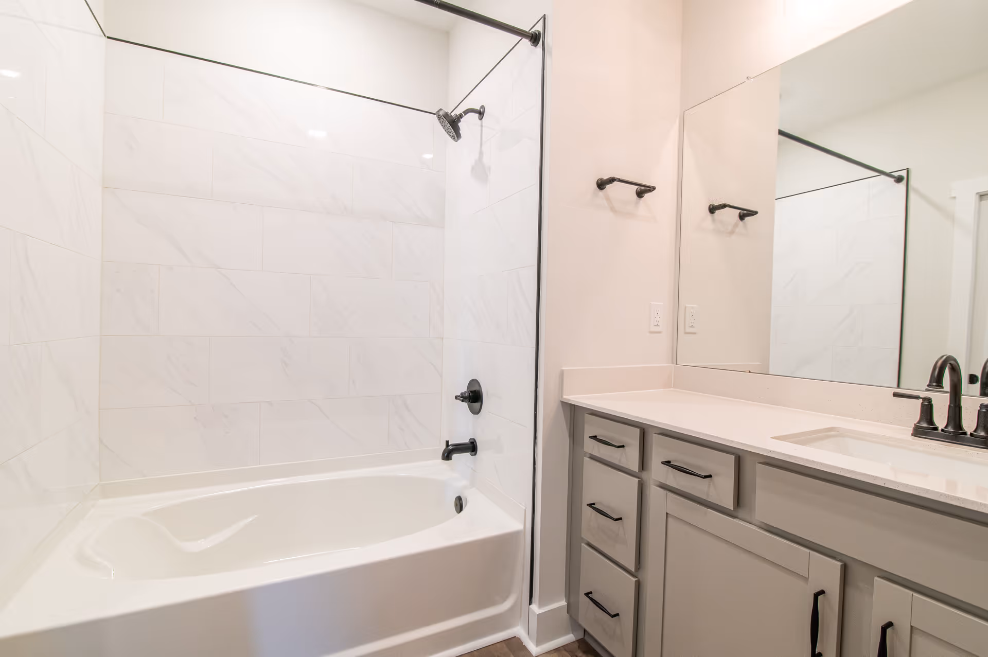 Clean modern bathroom with a bathtub-shower combo, tiled walls, and a vanity with sink and mirror.
