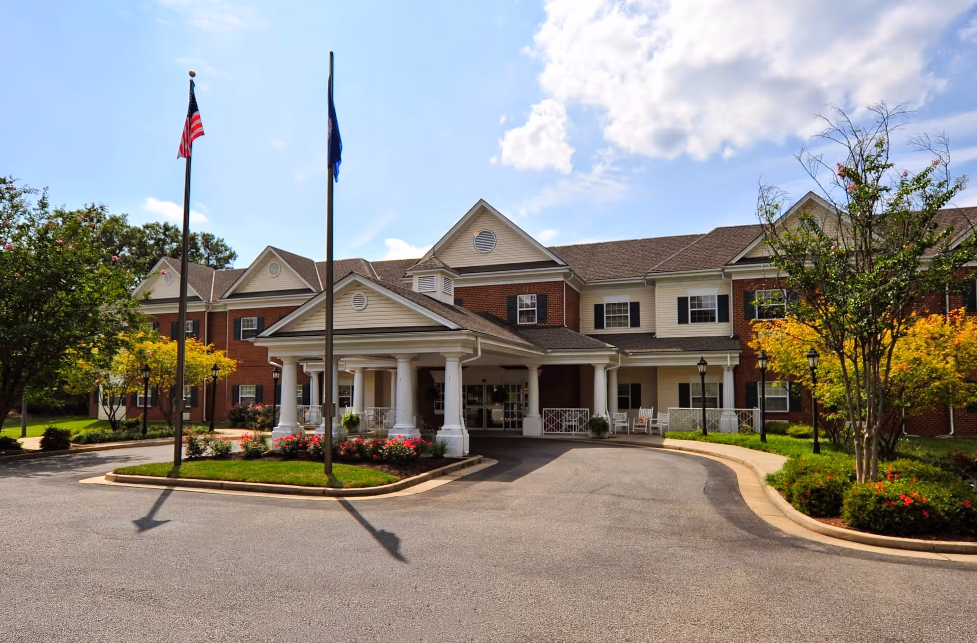 Exterior view of Charter Senior Living of Williamsburg with flags and landscaped entrance.
