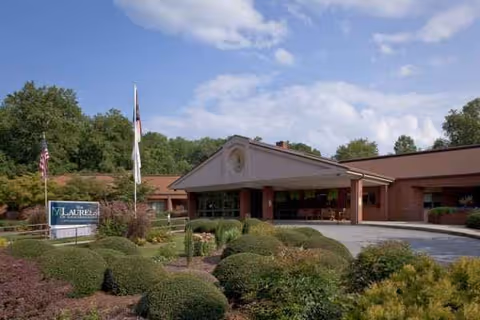 Front view of The Laurels of GreenTree Ridge entrance with landscaped shrubs and flags.