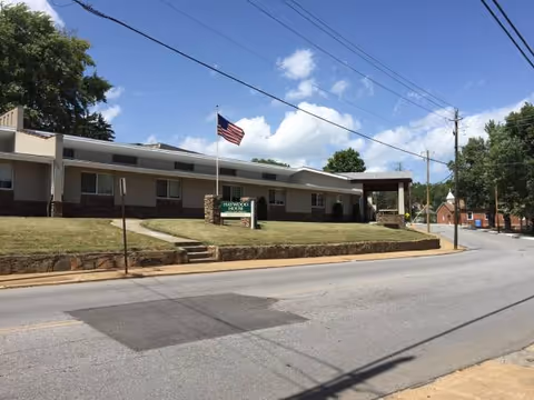 Exterior view of Haywood House senior living facility with flag and lawn.