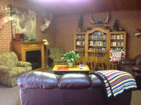 Cozy brick-walled living room with leather sofa, fireplace, and a tall wooden bookcase.