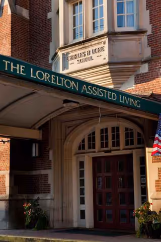 Exterior view of The Lorelton Assisted Living entrance with green awning and flag.