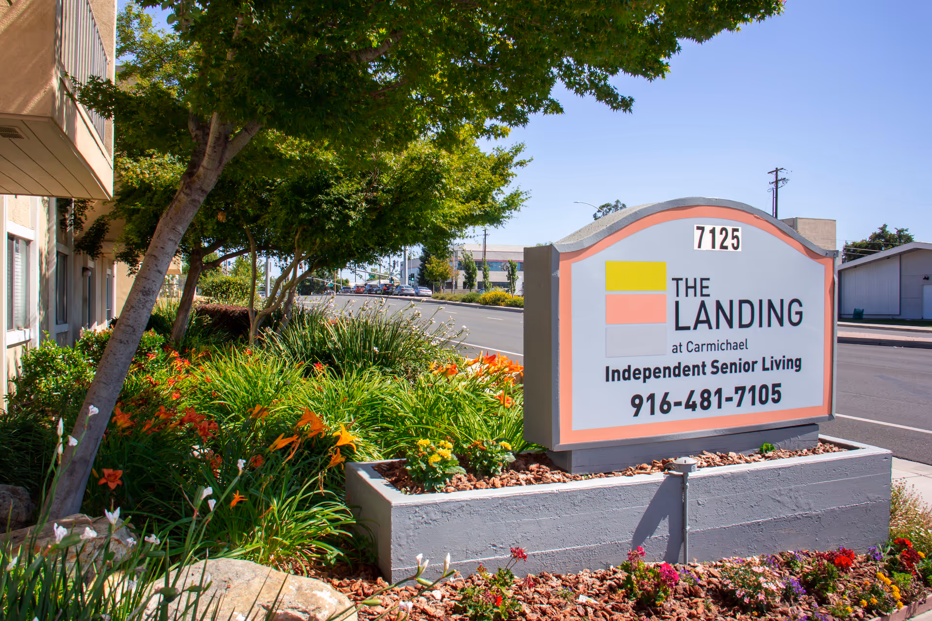 Front exterior sign for The Landing at Carmichael, independent senior living, with landscaped bed.