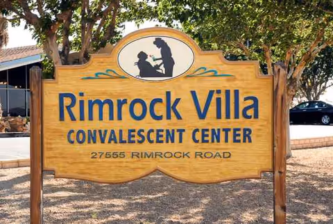 Large wooden sign for Rimrock Villa Convalescent Center with trees behind.