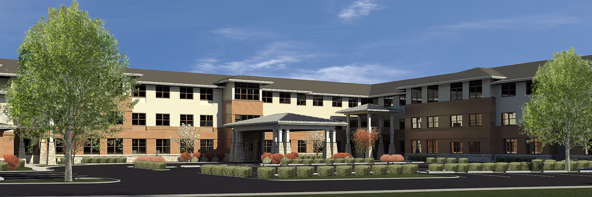 Exterior view of a modern three-story senior living facility building with a covered entrance, surrounded by landscaped bushes and trees under a blue sky.