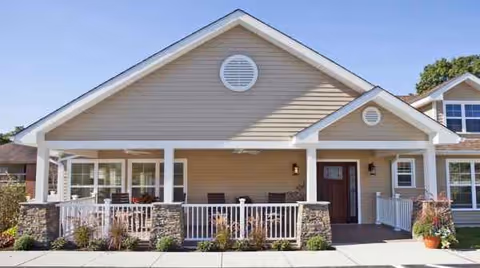 Front exterior of a senior living facility with a covered porch and seating.
