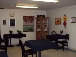 A small dining room with dark tables, chairs, wall decor, and a wooden cabinet.