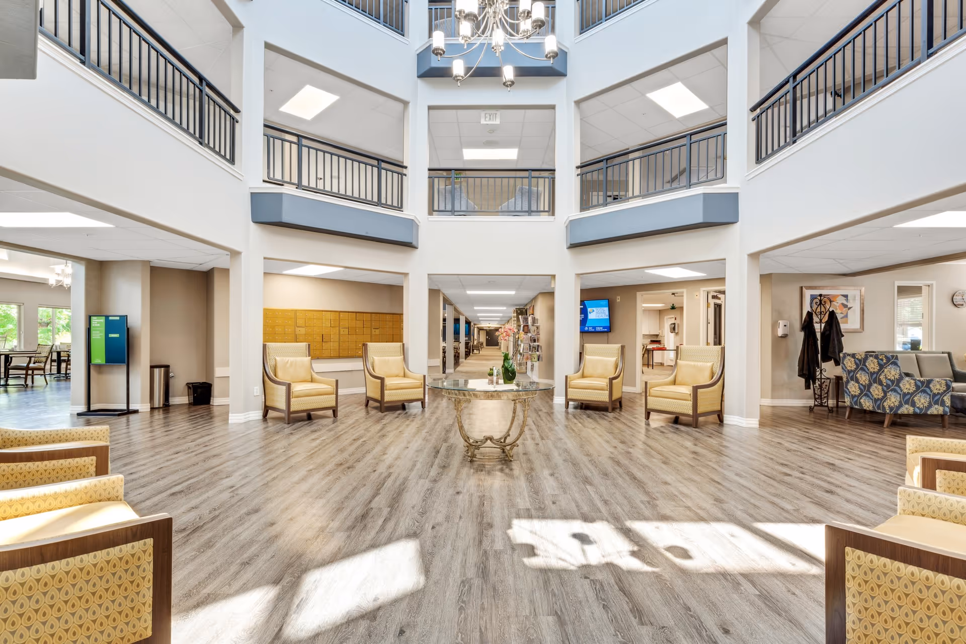 Spacious two-story atrium lobby with seating, a central table, chandelier, and upper-level balconies.