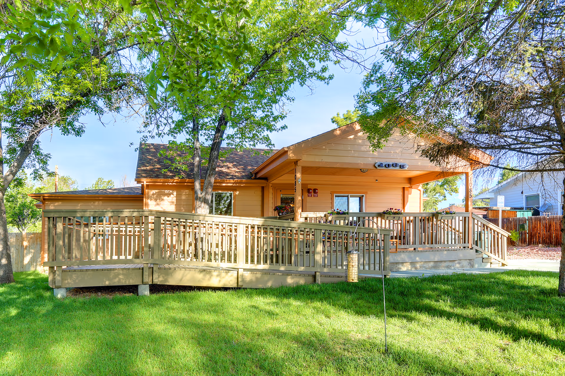 A single-story orange building with a wooden ramp and green front lawn.