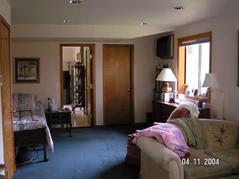 Cozy living area in a private nursing suite with sofa, bed, lamps, and window.