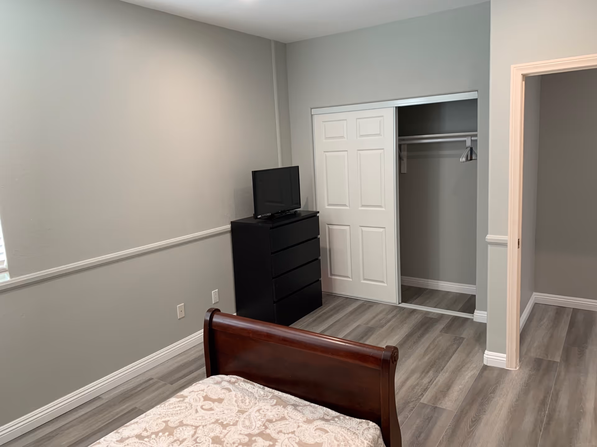 A simple bedroom featuring a bed, a TV, and a closet.