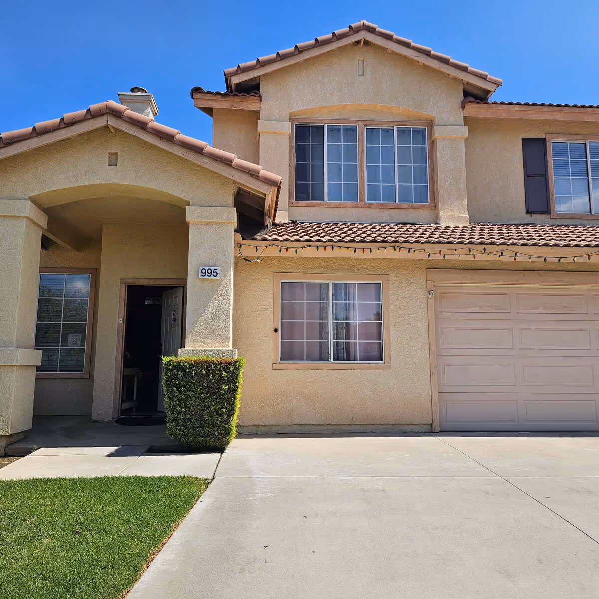 Two-story beige home with a tiled roof, front window, and attached garage.