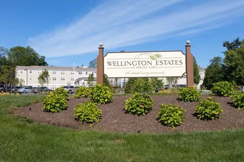 Wellington Estates entrance sign with landscaped shrubs and building in the background.