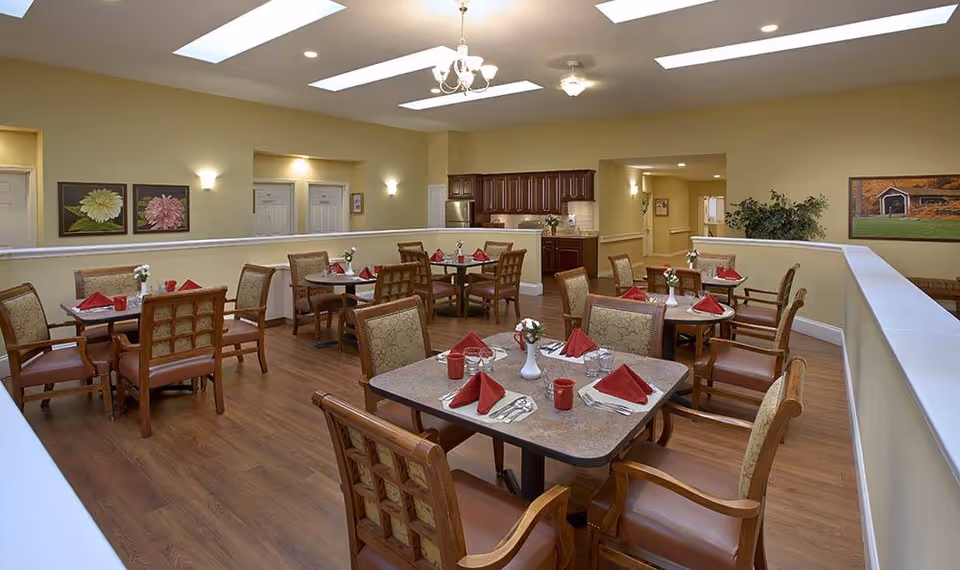 Spacious dining room with multiple set tables and chairs, wood flooring, and a service counter in the back.