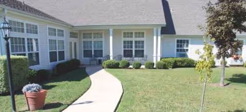 Front exterior of Brookdale Georgetown with curved walkway, lawn, shrubs, and entrance columns.