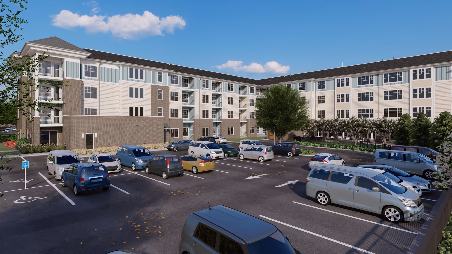 Exterior view of a multi-story senior living facility building with a parking lot in front. Several cars are parked in the lot, including handicapped parking spaces. The building has light blue and beige siding with multiple windows and balconies. Trees and shrubs are planted around the parking area under a clear blue sky with a few clouds.