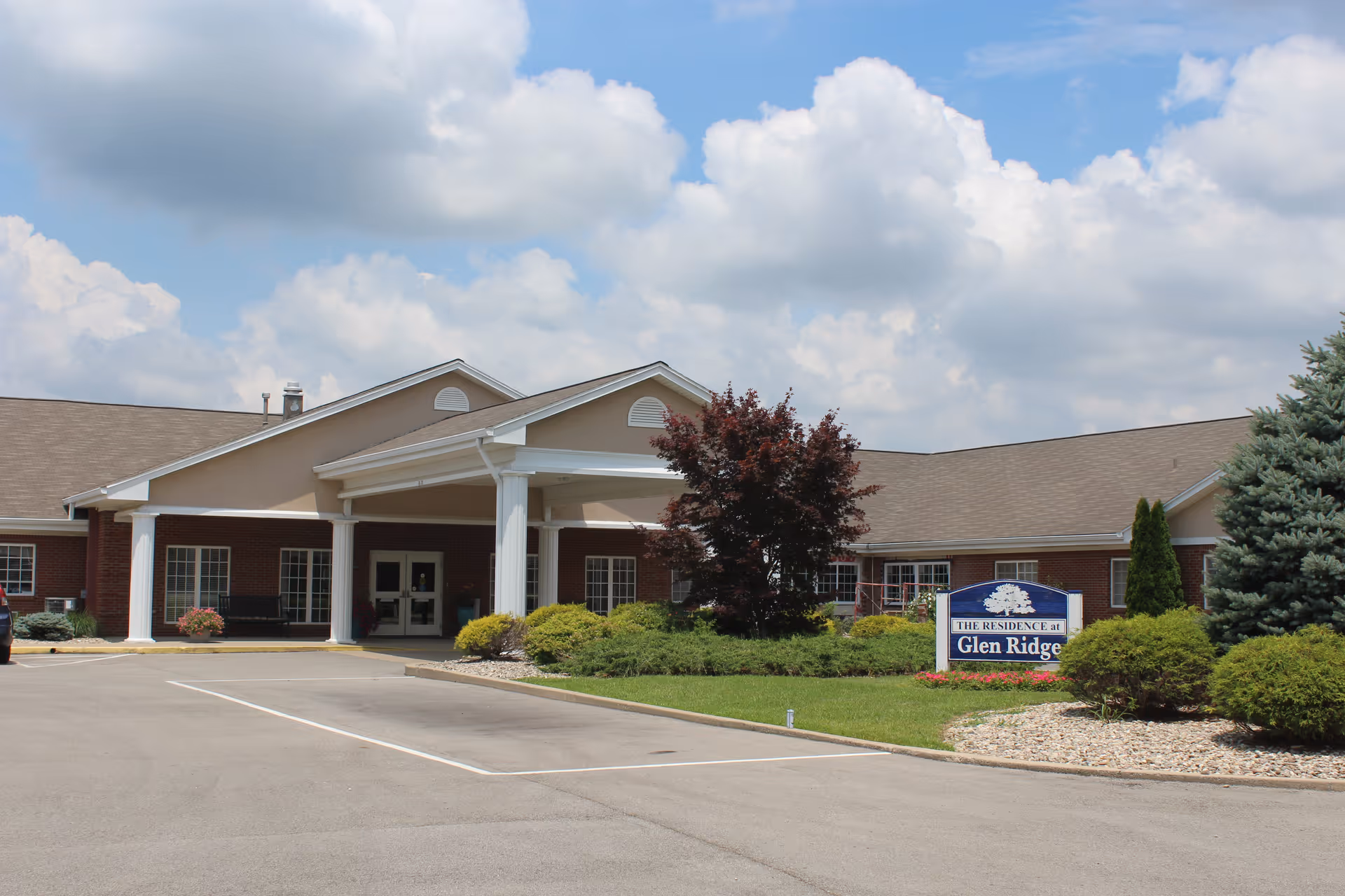 Front exterior of Glen Ridge Health Campus showing the main entrance, landscaped grounds, and a sign by the driveway.